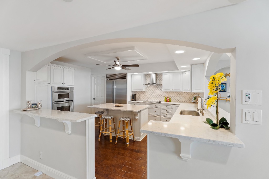 Chef's kitchen with white cabinets, center island, stainless appliances and herringbone tile backsplash