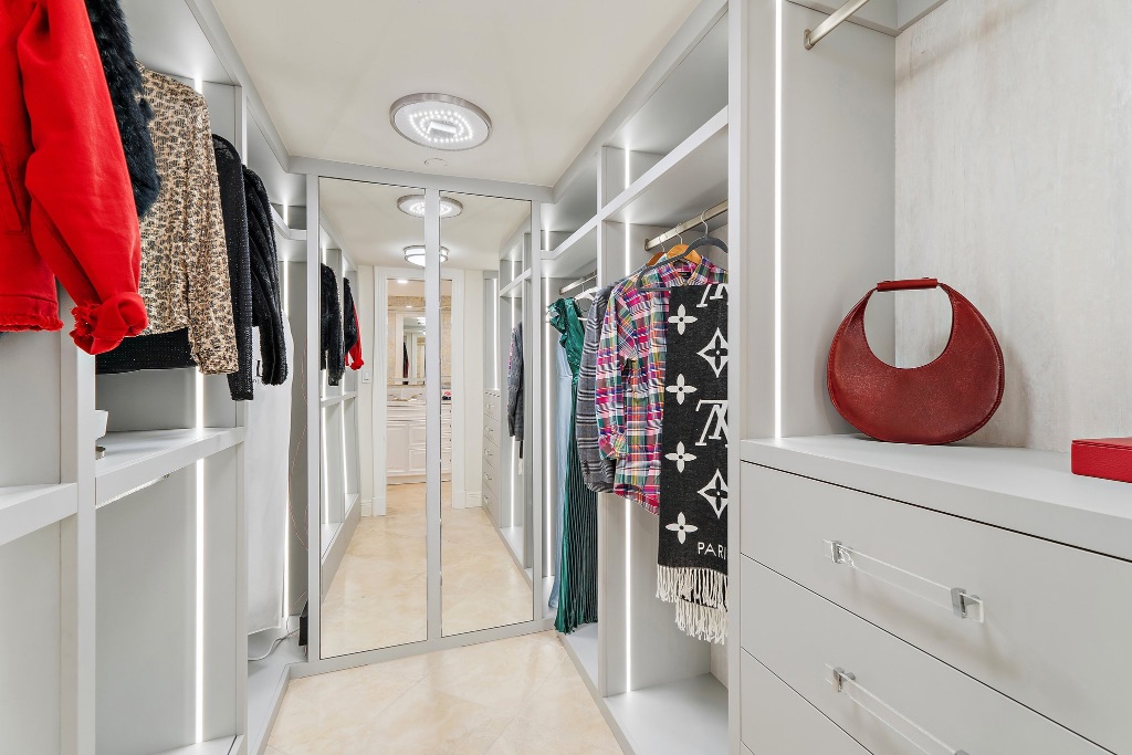 Primary suite custom walk-in closet with LED lighting, full-length mirrors and white cabinetry