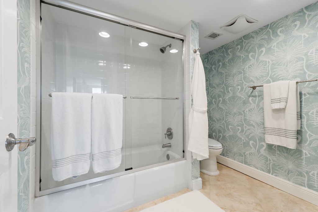 Guest bathroom with flamingo wallpaper and tub/shower combo