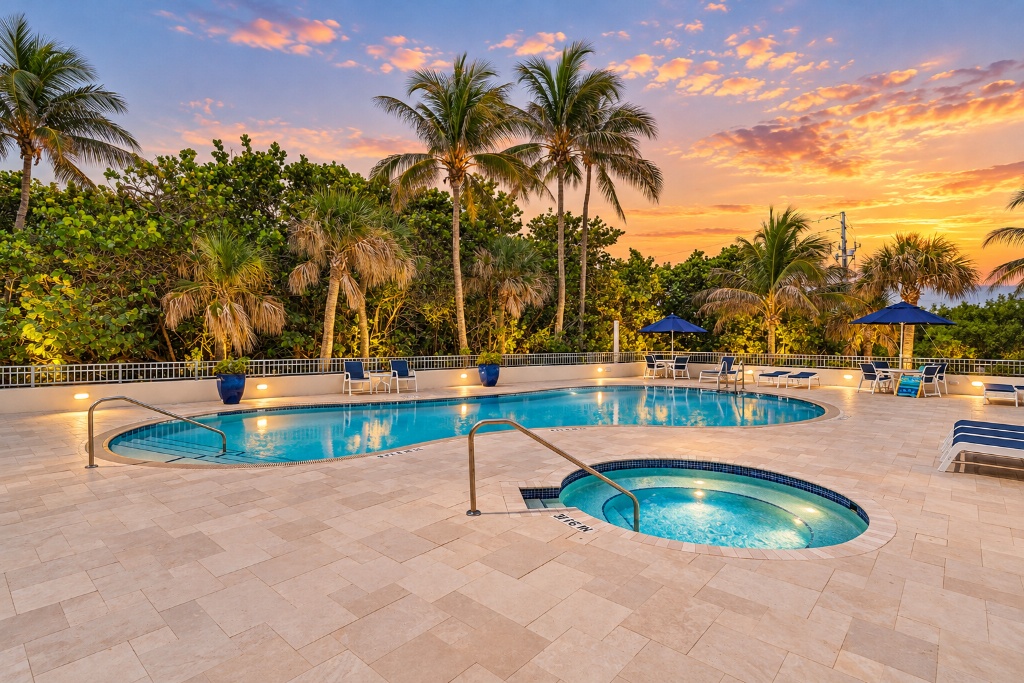 Community pool and spa at sunset with palm trees and lounge chairs