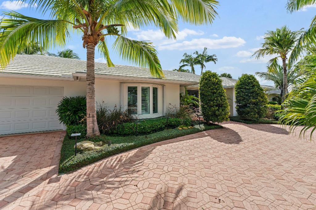 Front exterior — garage, shuttered windows, tropical landscaping