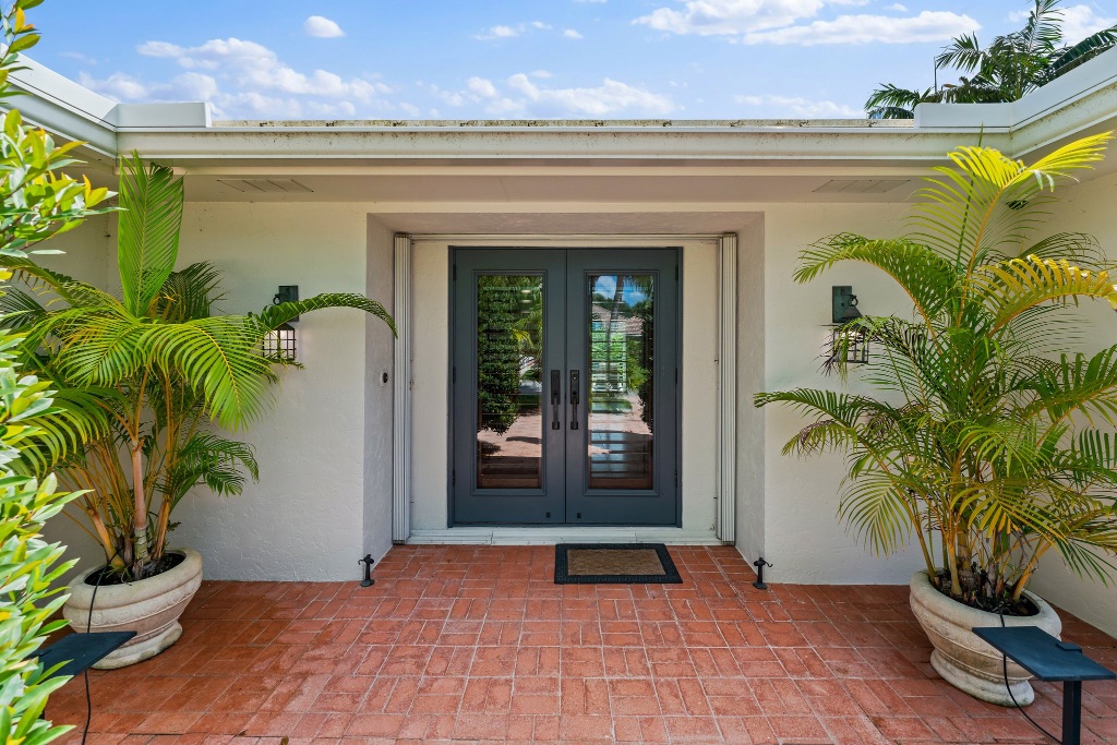 Front entry — elegant double glass doors with flanking areca palms