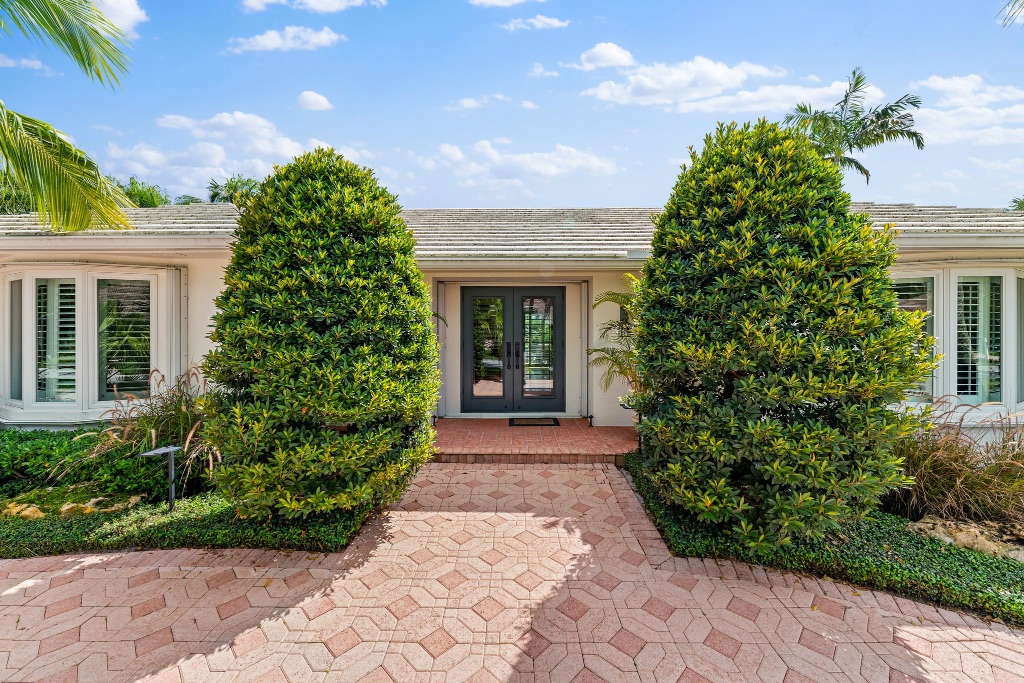 Front entry path with manicured hedges and lush tropical planting