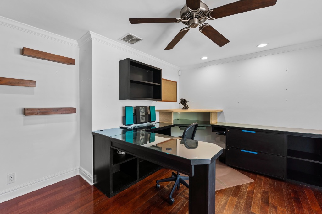 Home office with L-shaped built-in desk and rich hardwood floors
