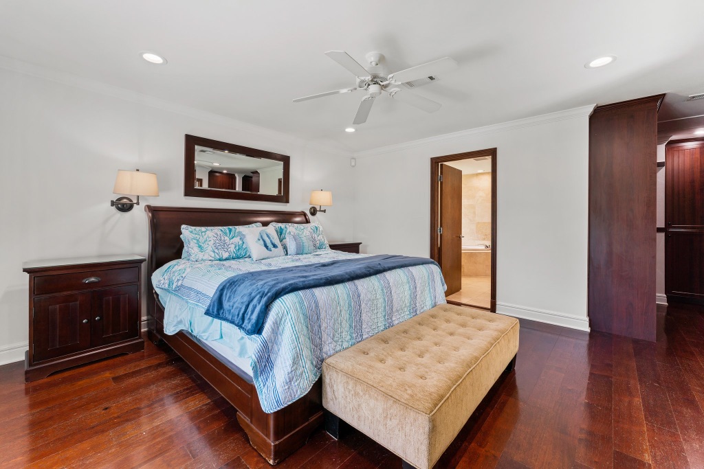 Primary suite — king sleigh bed, tufted bench, hardwood floors