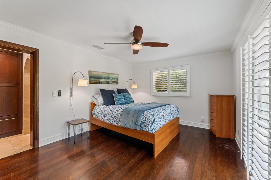 Guest bedroom — queen bed with plantation shutters and hardwood floors