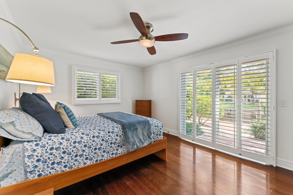 Guest bedroom — floor-to-ceiling plantation shutters and tropical views