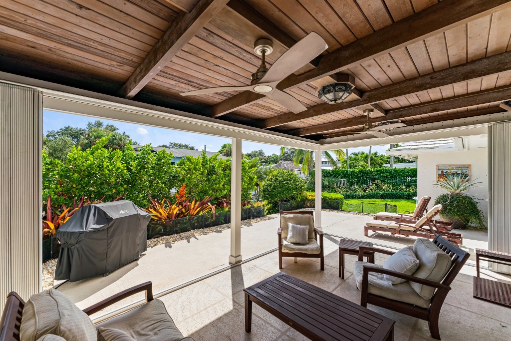 Covered lanai — stained wood-beam ceiling with ceiling fans and outdoor lounge