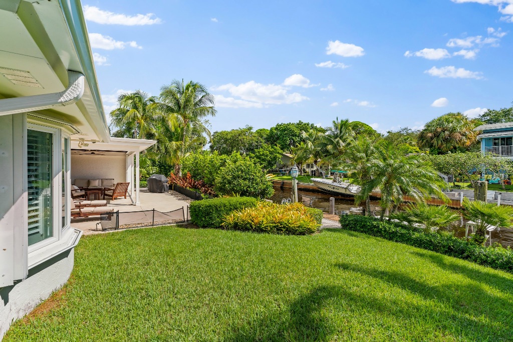 Lush tropical backyard with covered lanai and 95-ft canal frontage