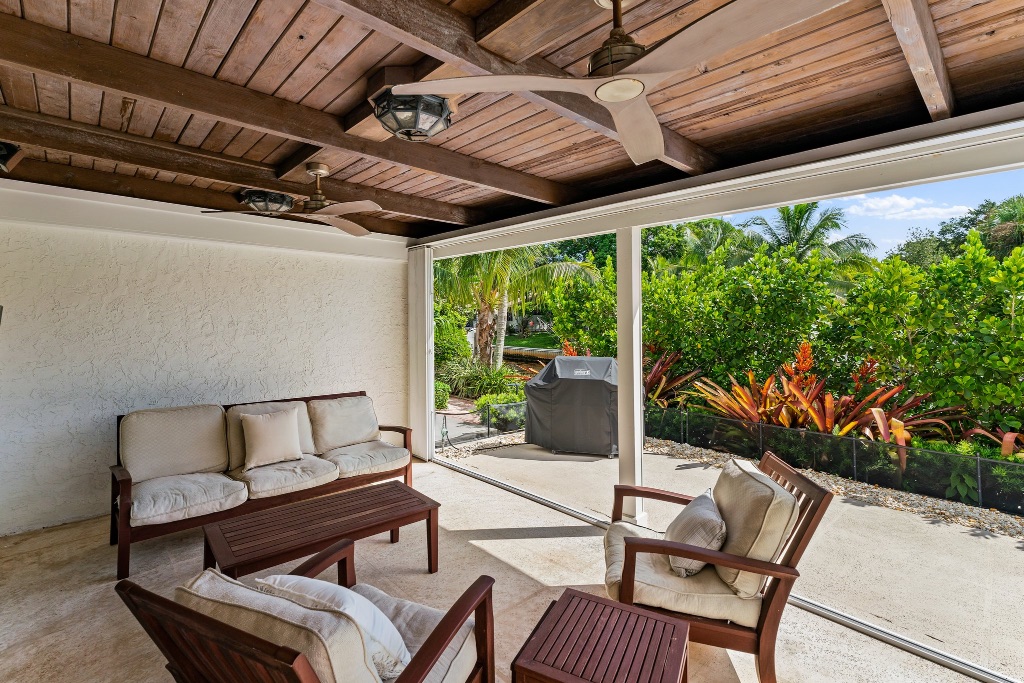 Covered outdoor lanai with lounge seating and glass-panel railing
