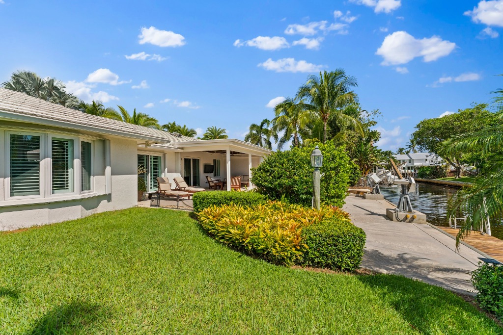 Manicured tropical lawn leading to covered lanai and private dock