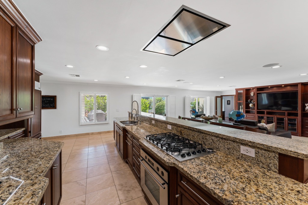 Gourmet kitchen — chef's gas cooktop, stainless ceiling hood and granite island