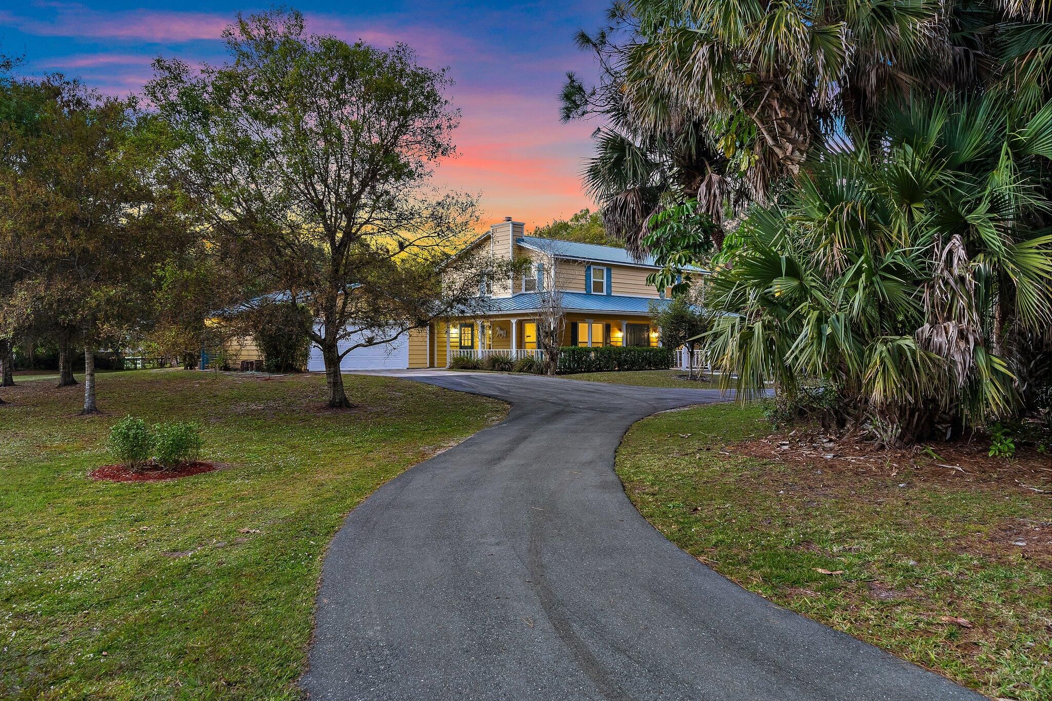 17375 Thunder Road Jupiter FL — twilight driveway approach through palms at sunset