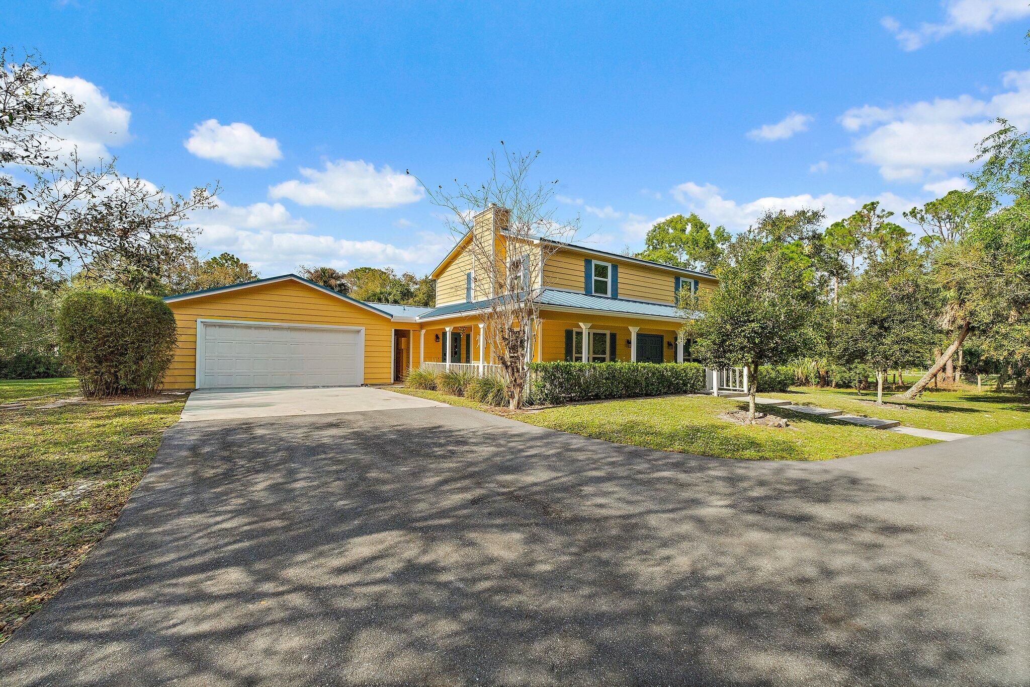 17375 Thunder Road — full front elevation with yellow siding, blue metal roof and garage