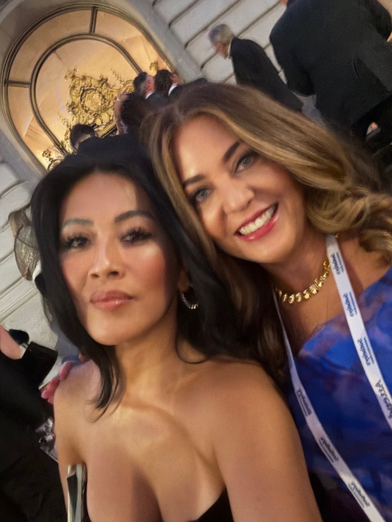 Two Sotheby's International Realty advisors wearing event lanyards take a close-up photo together outside San Francisco City Hall during the 50th anniversary evening gala