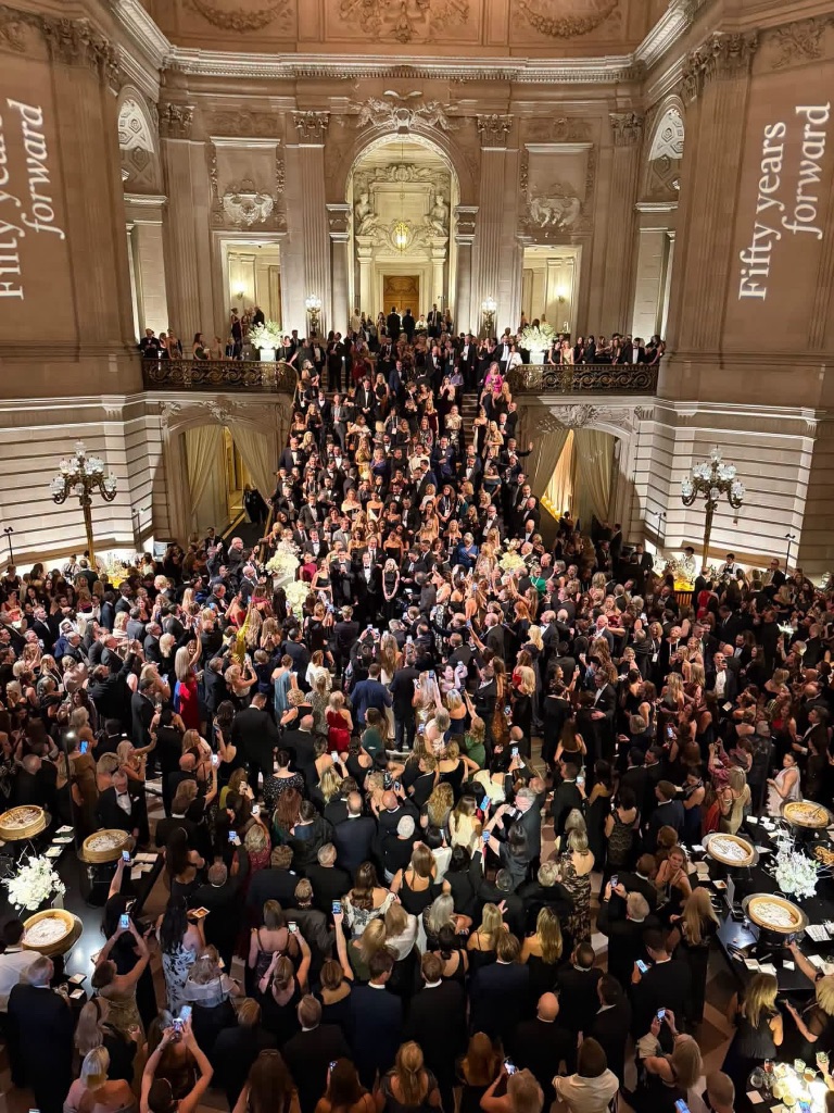 Hundreds of black-tie guests fill the grand staircase of San Francisco City Hall under 'Fifty Years Forward' projections at the Sotheby's International Realty 50th anniversary gala