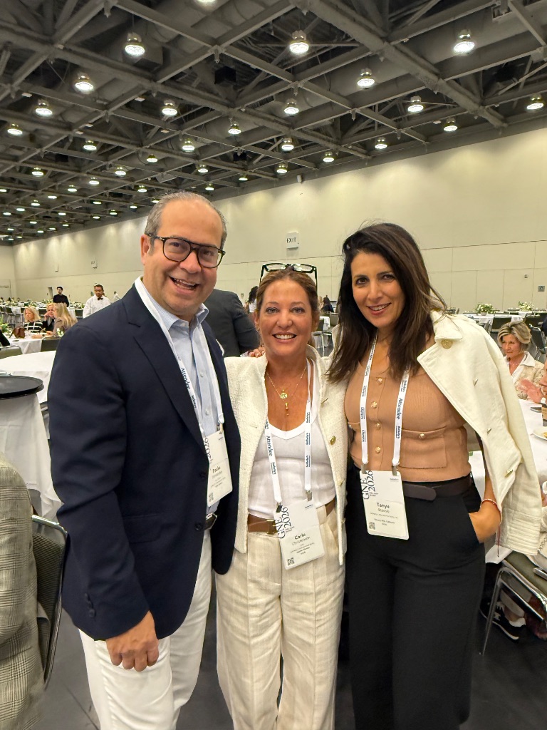Three Sotheby's International Realty professionals with conference lanyards connect at the 2026 Global Networking Event convention center in San Francisco