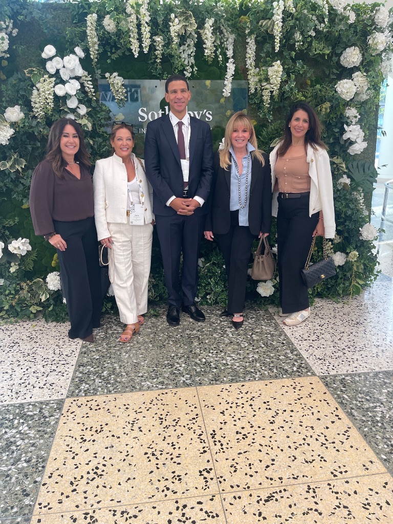 Five Sotheby's International Realty professionals pose in front of the official branded floral backdrop at the 2026 Global Networking Event in San Francisco