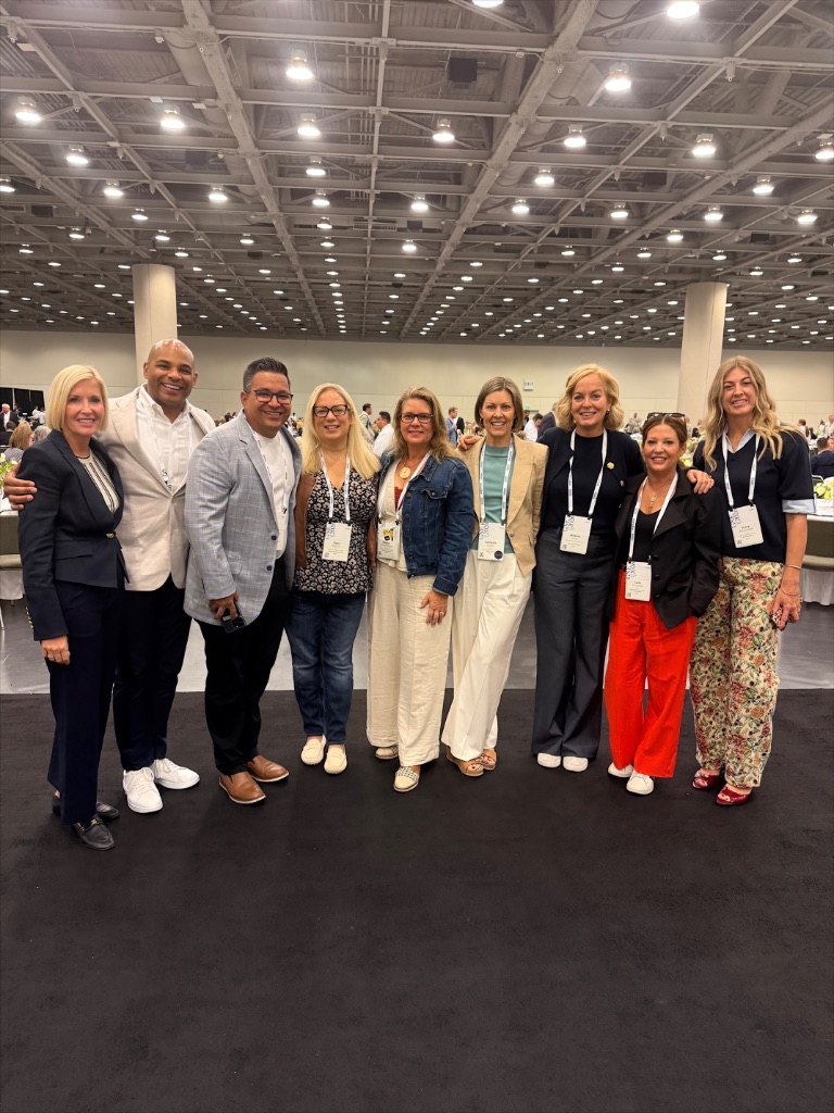 Nine ONE Sotheby's International Realty advisors in conference attire smile together on the exhibition floor at the 2026 Global Networking Event in San Francisco